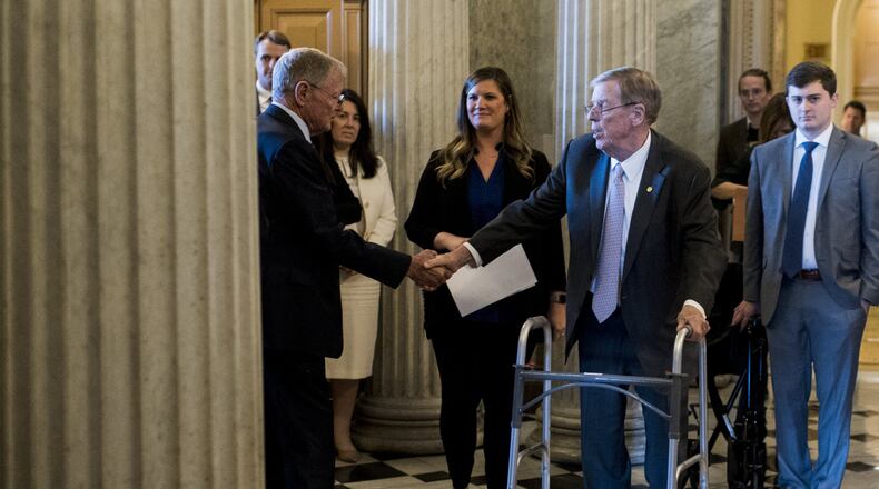 U.S. Sen. Johnny Isakson, R-Ga., right, shakes hands with U.S. Sen. Jim Inhofe, R-Okla., as he walks to the Senate floor to deliver his farewell address Tuesday in the Capitol. Isakson is stepping down at the end of the year for health reasons. (Photo By Bill Clark/CQ Roll Call via AP Images)