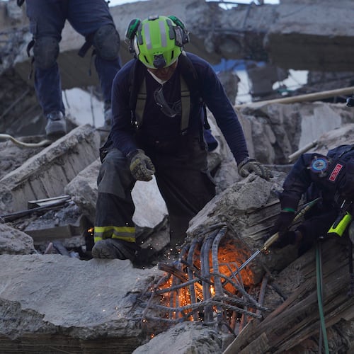Rescue workers cut through debris as they search for survivors the day after an earthquake struck Cali, Colombia, Tuesday, Aug. 11, 2026. (AP Photo/Ivan Valencia)