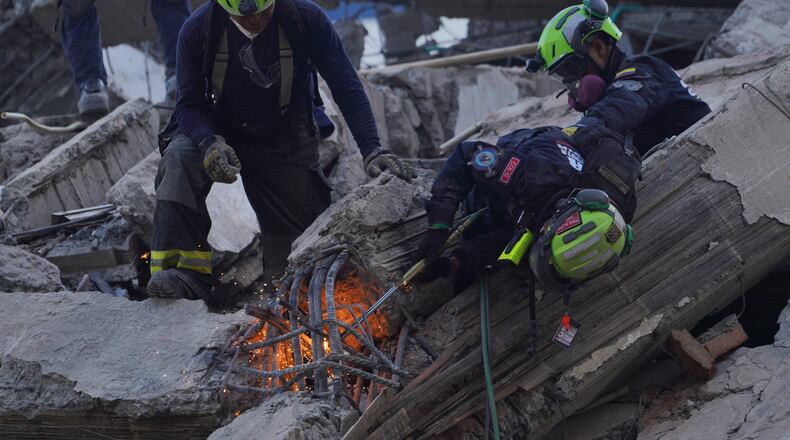 Rescue workers cut through debris as they search for survivors the day after an earthquake struck Cali, Colombia, Tuesday, Aug. 11, 2026. (AP Photo/Ivan Valencia)