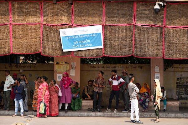 People wait for a bus at a cool bus stop in Ahmedabad, India, Wednesday, April 2, 2025. (AP Photo/Ajit Solanki)