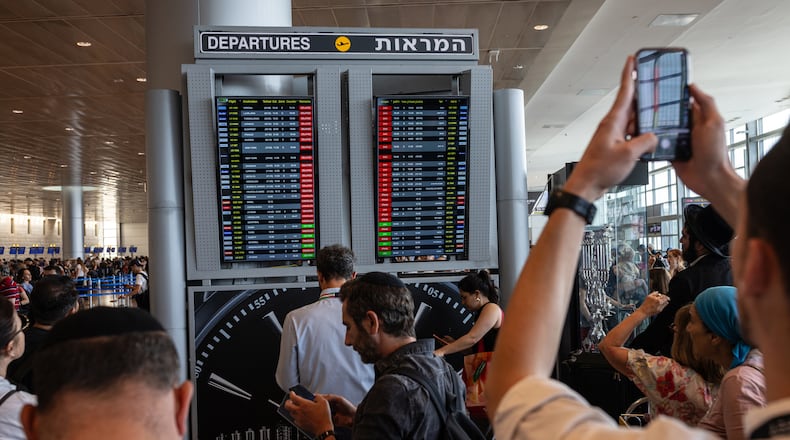 Travellers check the status of the flights at Ben Gurion International Airport outside Tel Aviv on Tuesday, Oct. 10, 2023. (Tamir Kalifa/The New York Times)