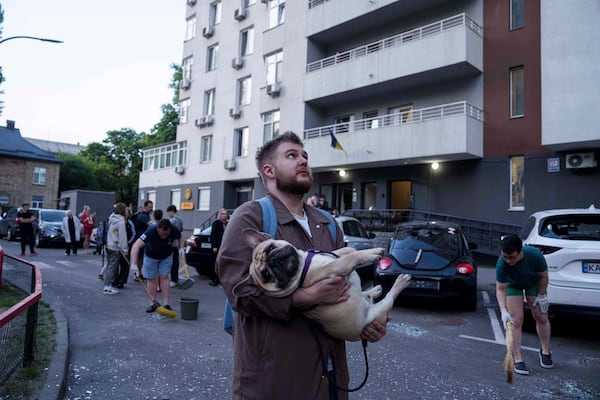 A man carries his dog in front of a residential multi-storey building damaged after a Russian drone strike on Kyiv, Ukraine, on Friday, June 6, 2025. (AP Photo/Evgeniy Maloletka)