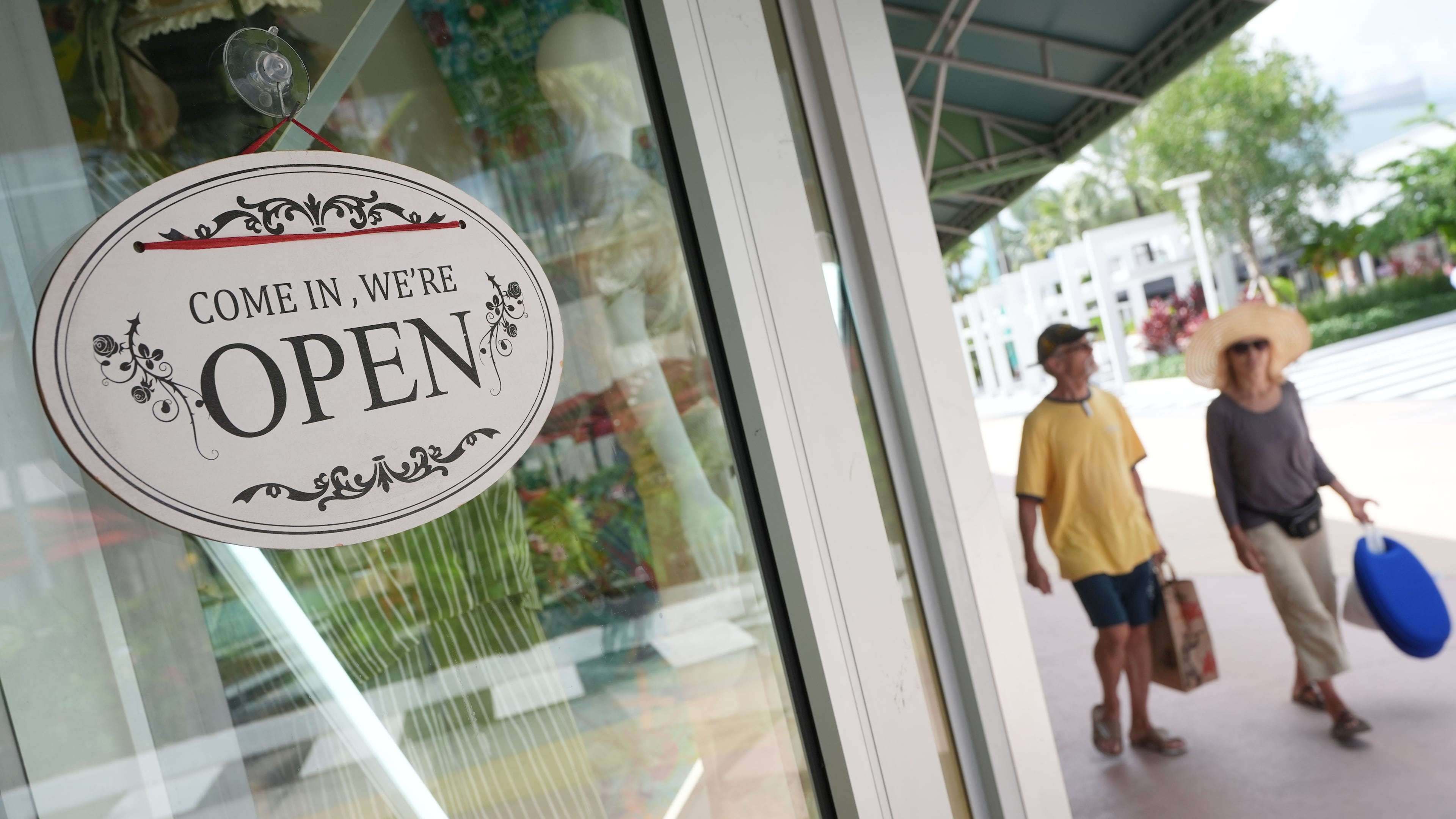 Shoppers walk by a clothing store, Thursday, Sept. 25, 2025, in Miami Beach, Fla. (AP Photo/Marta Lavandier)