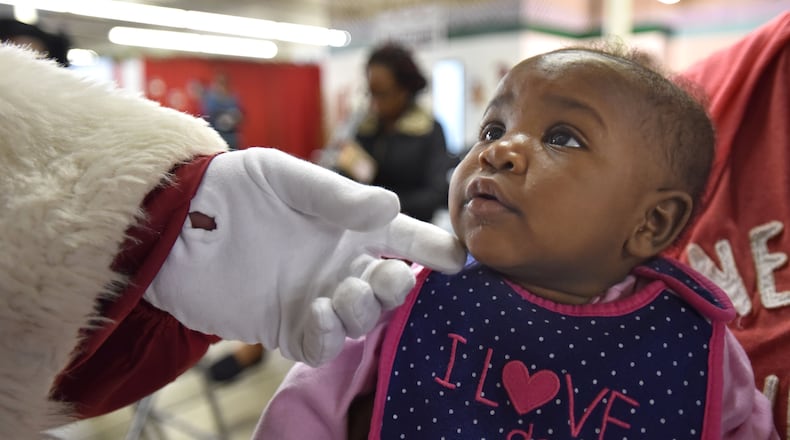 From Dec. 1, 2015: Seven-month-old Kailin Wright looks up Santa Claus (George Wieder) as he touches her cheek at Santa's Village in Atlanta. Each year, parents and guardians of more than 40,000 children come to Santa's Village to select gift items for their children. Santa's Village is The Empty Stocking Fund's gift distribution center for Fulton and DeKalb counties.