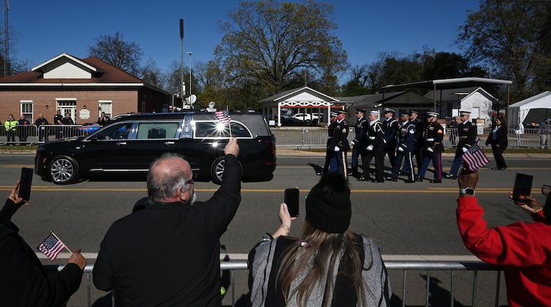 Mourners watch former first lady Rosalynn Carter's motorcade moving through downtown Plains Wednesday, November 29, 2023, in Plains. (Hyosub Shin / Hyosub.Shin@ajc.com)