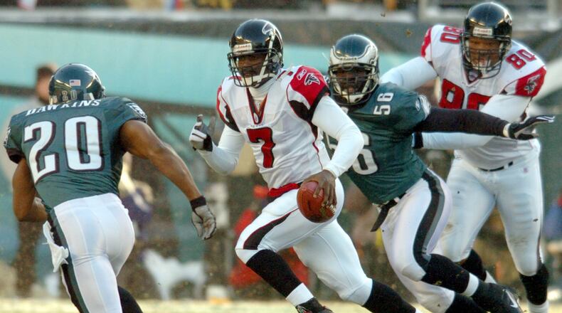 Falcons quarterback Mike Vick scrambles upfield for a long run under pursuit by Eagles Brian Dawkins (20) and Derrick Burgess (56) while Falcons' end Eric Beverly (80) makes the block in the backfield in the first quarter of the NFC Championship game at Lincoln Financial Field on Sunday, January 23, 2005. (CURTIS COMPTON/AJC staff)