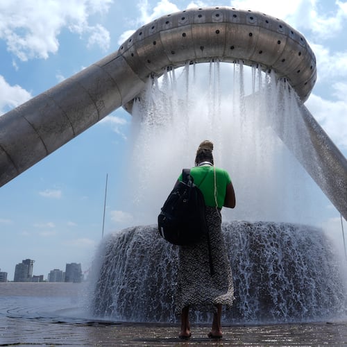 A woman stands in mist trying to cool off from hot weather at Dodge Fountain at Hart Plaza in Detroit, Tuesday, June 30, 2026. (AP Photo/Paul Sancya)