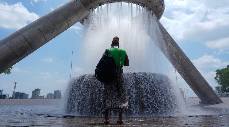 A woman stands in mist trying to cool off from hot weather at Dodge Fountain at Hart Plaza in Detroit, Tuesday, June 30, 2026. (AP Photo/Paul Sancya)