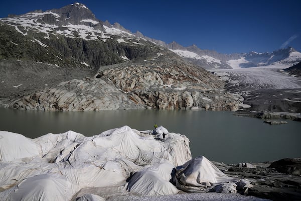 Workers prepare sheets to cover the Rhone Glacier near Goms, Switzerland, June 10, 2025. (AP Photo/Matthias Schrader)
