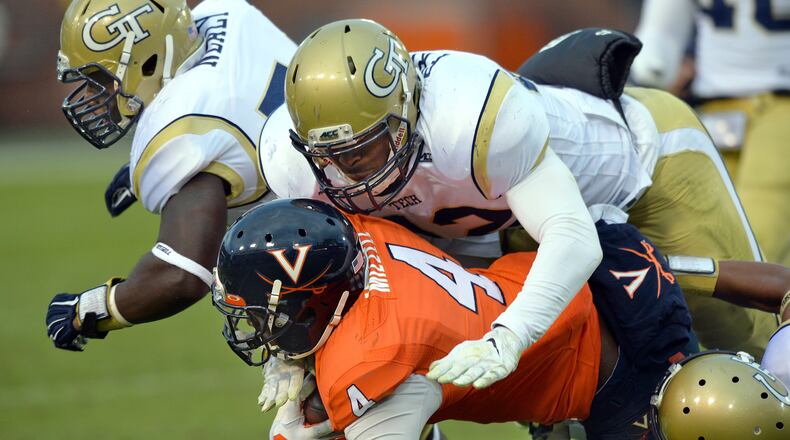Virginia Cavaliers running back Taquan Mizzell (4) is brought down by Georgia Tech Yellow Jackets defensive end KeShun Freeman (42) in the second half at Bobby Dodd Stadium on Saturday, November 1, 2014. Georgia Tech Yellow Jackets won 35-10 over the Virginia Cavaliers. HYOSUB SHIN / HSHIN@AJC.COM