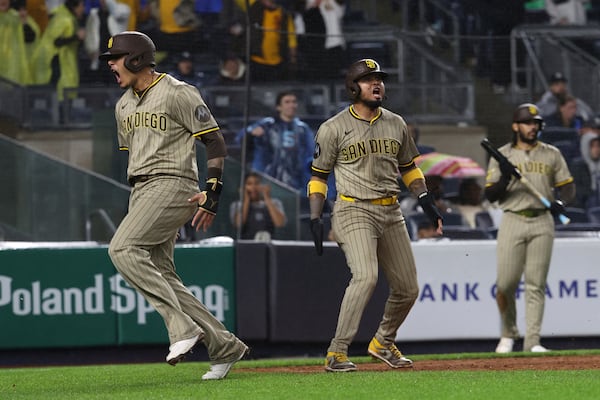 San Diego Padres' Manny Machado, left, and Luis Arraez, center, react after scoring on a single hit by Xander Bogaerts during the eighth inning of a baseball game against the New York Yankees, Monday, May 5, 2025, in New York. (AP Photo/Pamela Smith)
