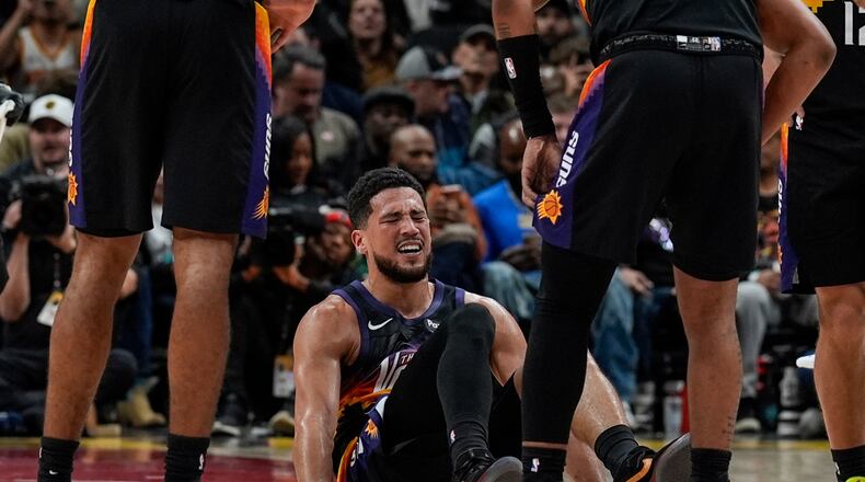 Phoenix Suns guard Devin Booker (1) winces in pain during the second half of an NBA basketball game against the Atlanta Hawks, Friday, Jan. 23, 2026, in Atlanta. (AP Photo/Mike Stewart)