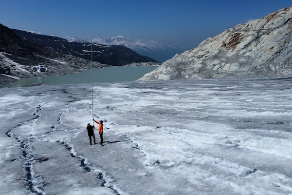 Matthias Huss, of the Federal Institute of Technology in Zurich and glacier monitoring group GLAMOS, and Monica Ursina Jaeger make measurements at the Rhone glacier near Goms, Switzerland, June 10, 2025. (AP Photo/Matthias Schrader)