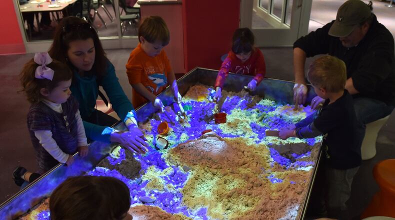 Kids and their parents play in a topographical sand box at the Children’s Museum of Atlanta. The sand changes colors based on the action of the children. Dig a hole and the sand turns blue for water. Pile the sand up and it turns brown to represent a mountain. The museum officially reopens Saturday, Dec. 12, after completely revamping the space. The $8.2 million project, which had been underway since August, includes a new 3,000-square-foot mezzanine level focused on STEM (science, technology, engineering, arts and math education), several new interactive exhibits, and a new performance space for the museum’s storytellers and other performers. This is the museum’s first major renovation since opening 12 years ago. The museum is designed for children from babies to age 8, but new features, particularly hands-on STEM projects, are aimed at appealing to older kids as well. BRANT SANDERLIN/BSANDERLIN@AJC.COM