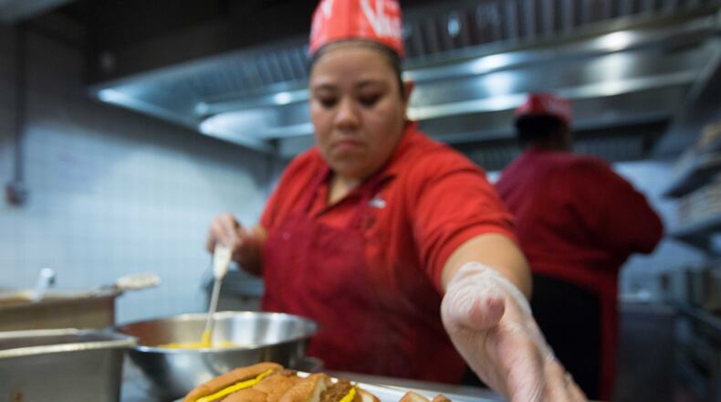 A woman makes chili dogs at The Varsity in downtown Atlanta. Now the chain’s owners are contemplating big changes. BRANDEN CAMP/SPECIAL