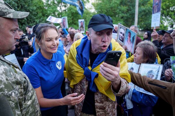A Ukrainian soldier speaks to a relative on a phone as he is walking through a human corridor of people holding photos of their missed relatives after returning from captivity after a POWs exchange between Russia and Ukraine, in Chernyhiv region, Ukraine, Thursday, June 26, 2025. (AP Photo/Evgeniy Maloletka)