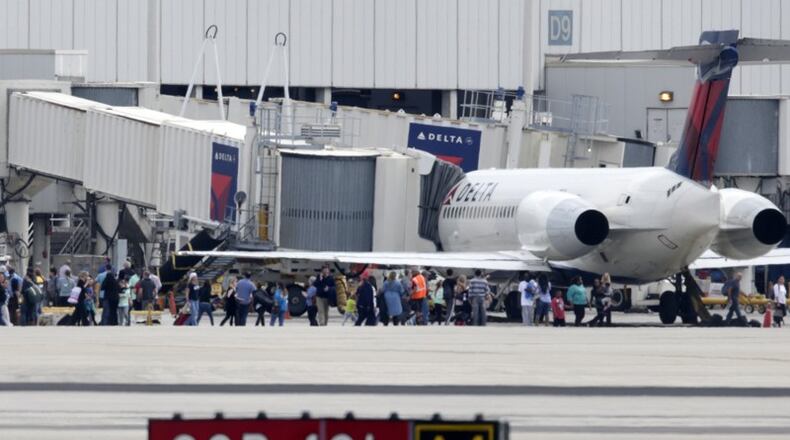 People stand on the tarmac at the Fort Lauderdale-Hollywood International Airport after a shooter opened fire inside the terminal, killing several people and wounding others before being taken into custody, Friday, Jan. 6, 2017, in Fort Lauderdale, Fla. (AP Photo/Lynne Sladky)