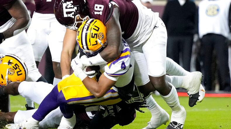 LSU running back John Emery Jr. (4) drags Texas A&M defensive lineman LT Overton (18) across the goal line for a touchdown during the first half of an NCAA college football game Saturday, Nov. 26, 2022, in College Station, Texas. (AP Photo/Sam Craft)