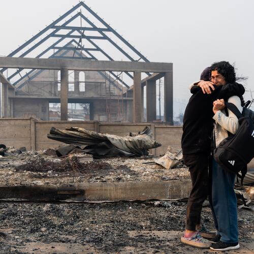 Mirtza Aguilera, right, and her daughter embrace in front of their home burned by wildfires in Tome, Chile, Monday, Jan. 19, 2026. (AP Photo/Javier Torres)