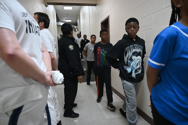 Students, with their hands behind their backs, react as they encounter inmates while walking down the hallway during a visit to the Athens-Clarke County Correctional Institution as part of a program that aims to curb youth crime and violence. (Hyosub Shin/AJC)