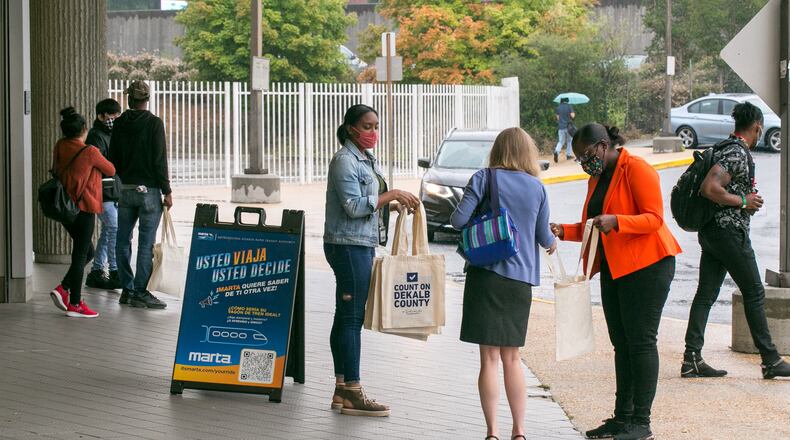 DeKalb County Election officials including Lamashia Davis, center, and Erin Austin, right, in orange, work to spread information about changes in voter laws and offer free voter IDs, if needed, on Wednesday, Sept 15, 2021 at the Chamblee MARTA Station.  (Jenni Girtman for The Atlanta Journal-Constitution)