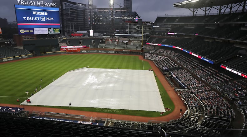 092420 Atlanta: Members of the Atlanta Braves ground crew adjust the infield tarp during a rain delay before playing the Miami Marlins in a MLB baseball game on Thursday, Sept. 24, 2020 in Atlanta. “Curtis Compton / Curtis.Compton@ajc.com”
