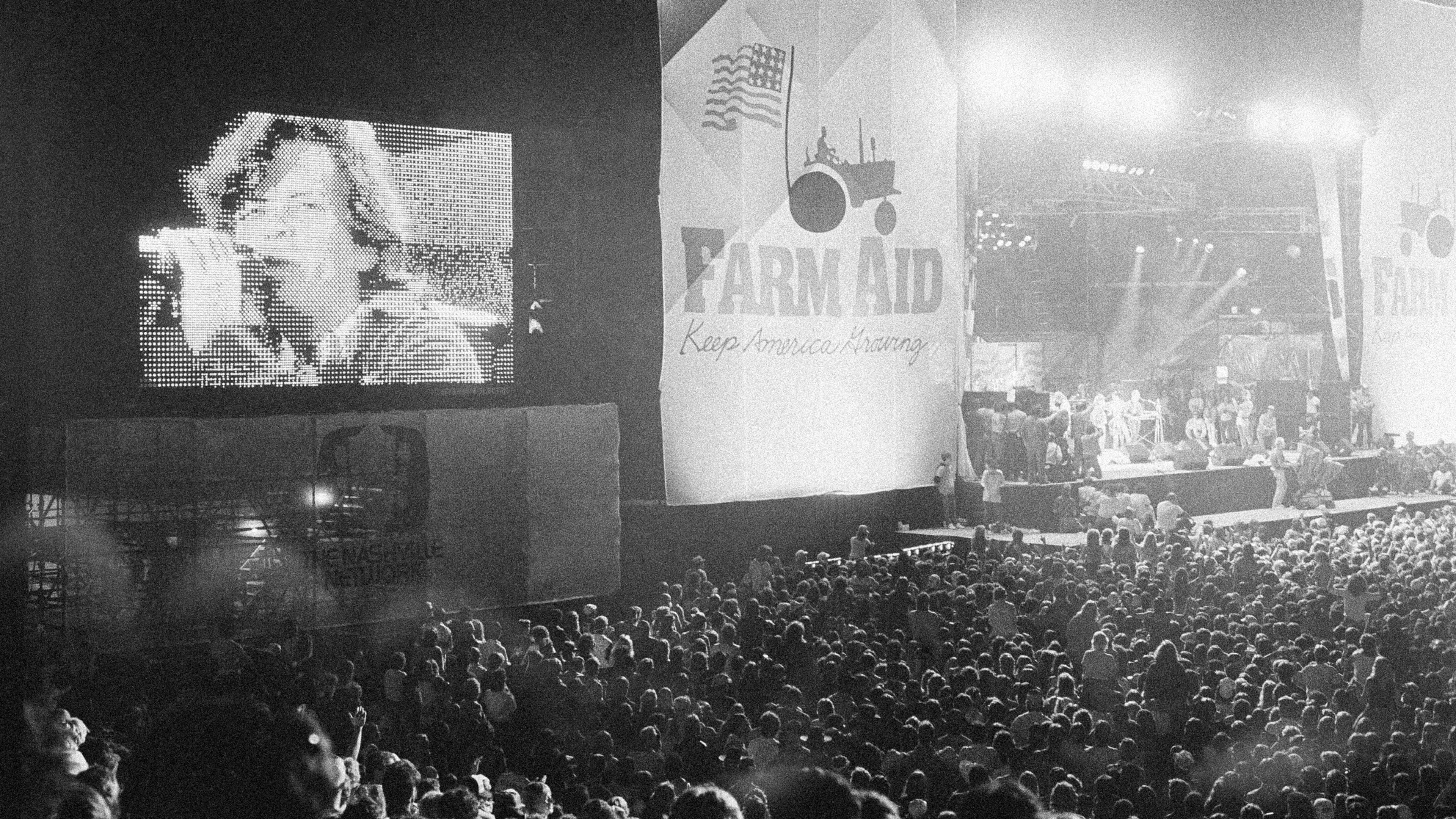 FILE - John Cougar Mellencamp performs both on stage and on one of two large screen television screens set up at the University of Illinois Memorial Stadium in Champaign, Ill. on Sept. 22, 1985 during the Farm Aid concert. (AP Photo/Seth Perlman, file)