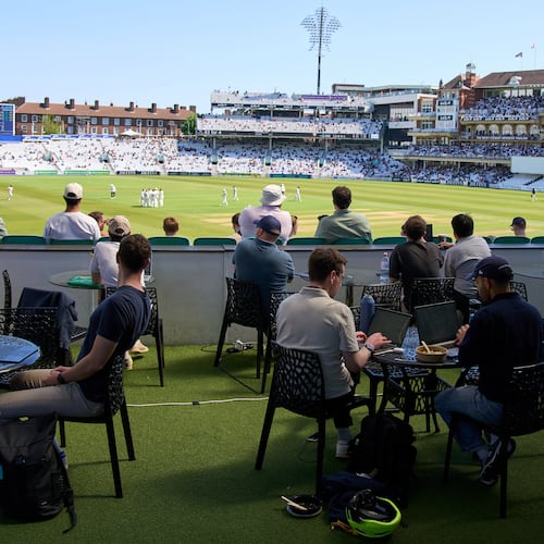 People work and watch cricket during a Surrey against Sussex County Championship cricket match at the Kia Oval in London, Friday, May 1, 2026. (AP Photo/Tony Hicks)