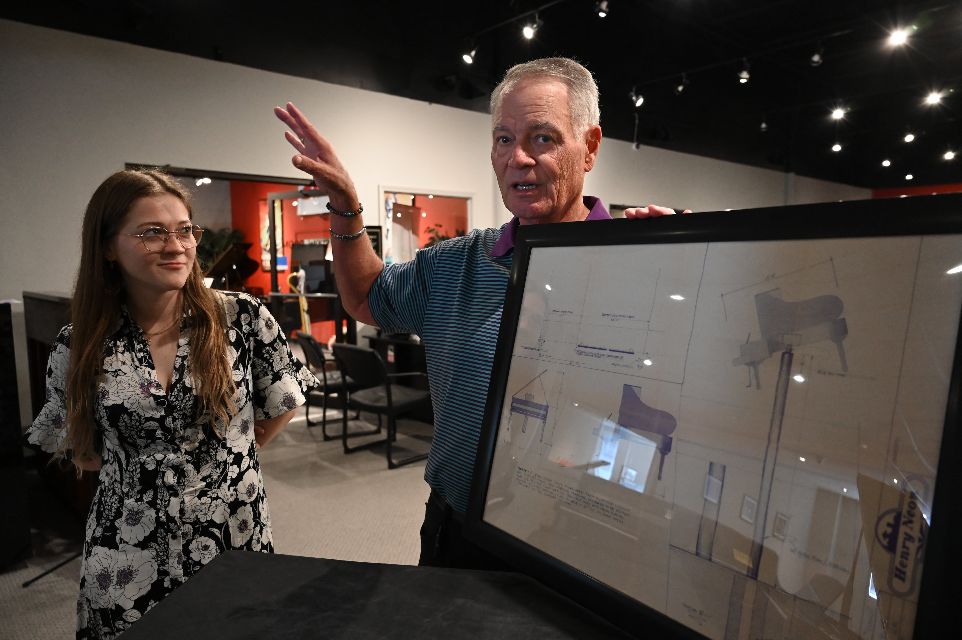 Blake Cooper shows a blueprint of the piano sign's original design at Cooper Piano in Brookhaven. (Hyosub Shin/AJC)