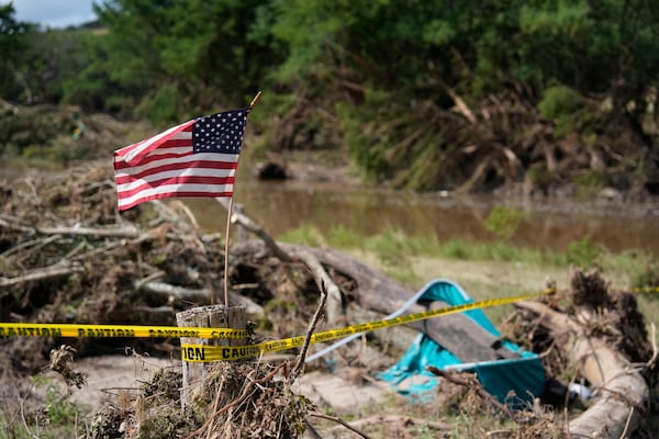 An American flag is placed on a stump in Kerrville, Texas on Tuesday, July 8, 2025. (AP Photo/Ashley Landis)