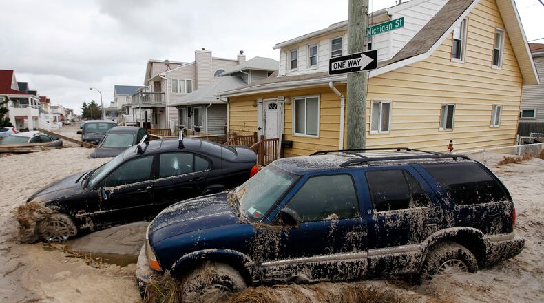 In this Oct. 30, 2012 file photo, cars lifted by floodwater are mired in several feet of sand in the aftermath of Superstorm Sandy, in Long Beach, N.Y.