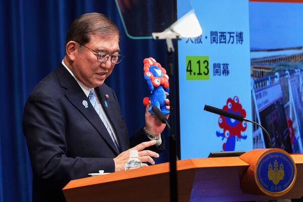 Japan Prime Minister Shigeru Ishiba shows Osaka Expo mascot Myaku-Myaku, a red-and-blue creature that symbolizes cell and water, as he speaks at a news conference at the prime minister's office in Tokyo, Japan, Tuesday, April 1, 2025. (Nicolas Datiche/Pool Photo via AP)