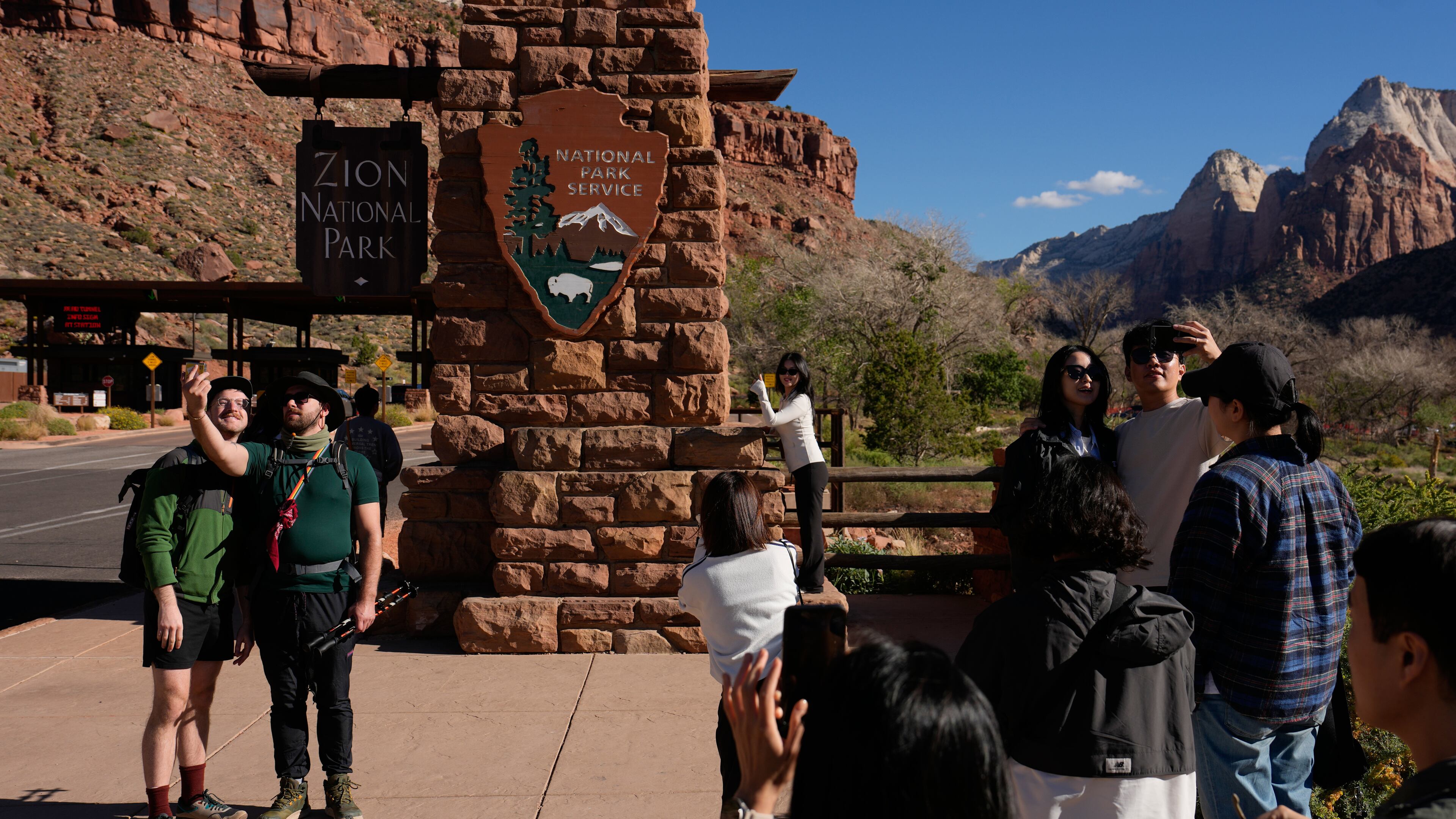 People stand near an entrance to Zion National Park, Wednesday, Oct. 1, 2025, in Springdale, Utah. (AP Photo/John Locher)
