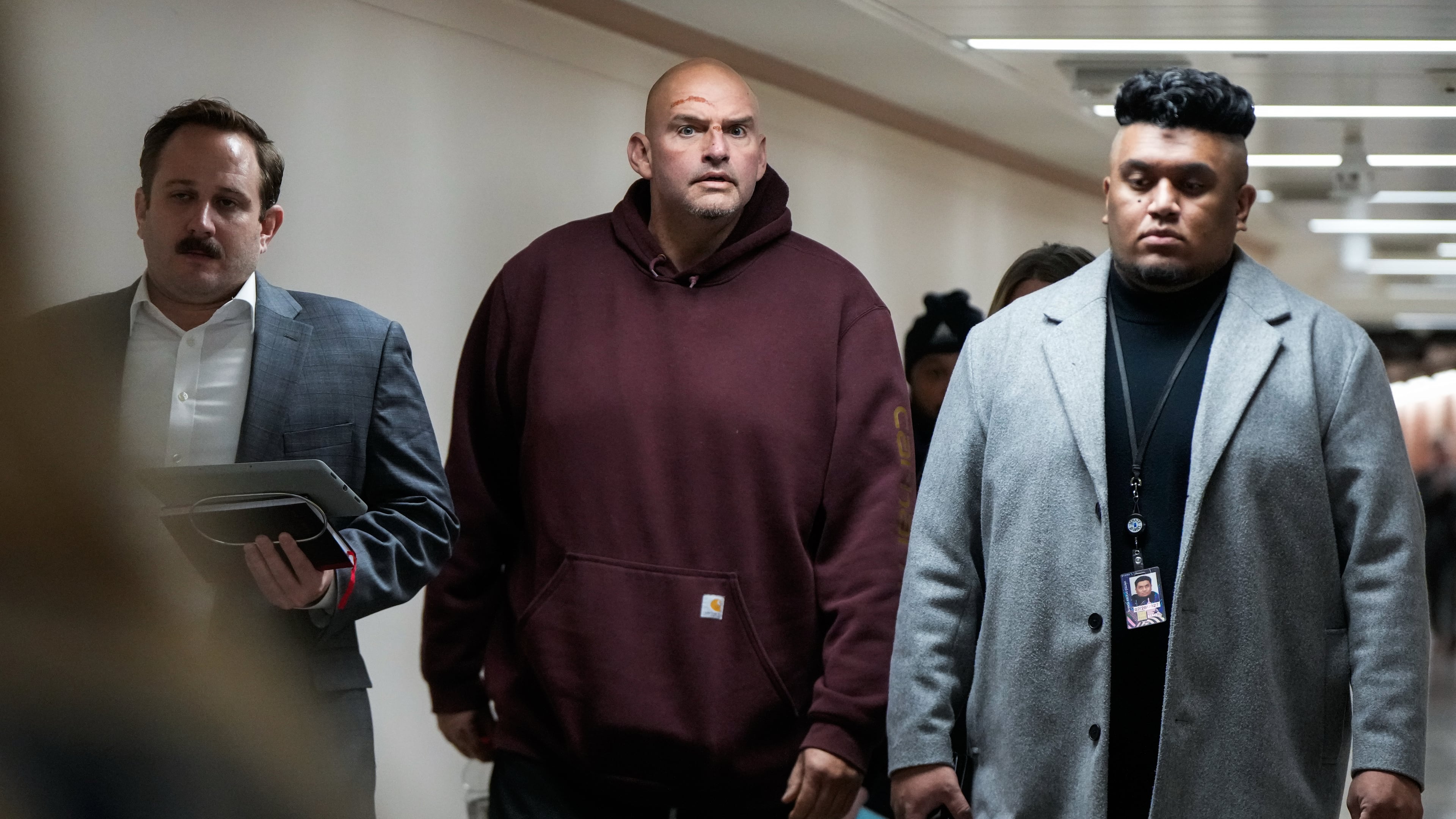 Injuries from a fall are seen on the face of Sen. John Fetterman, D-Pa., second from left, as he walks through a hallway on Capitol Hill, Wednesday, Nov. 19, 2025, in Washington. (AP Photo/Julia Demaree Nikhinson)
