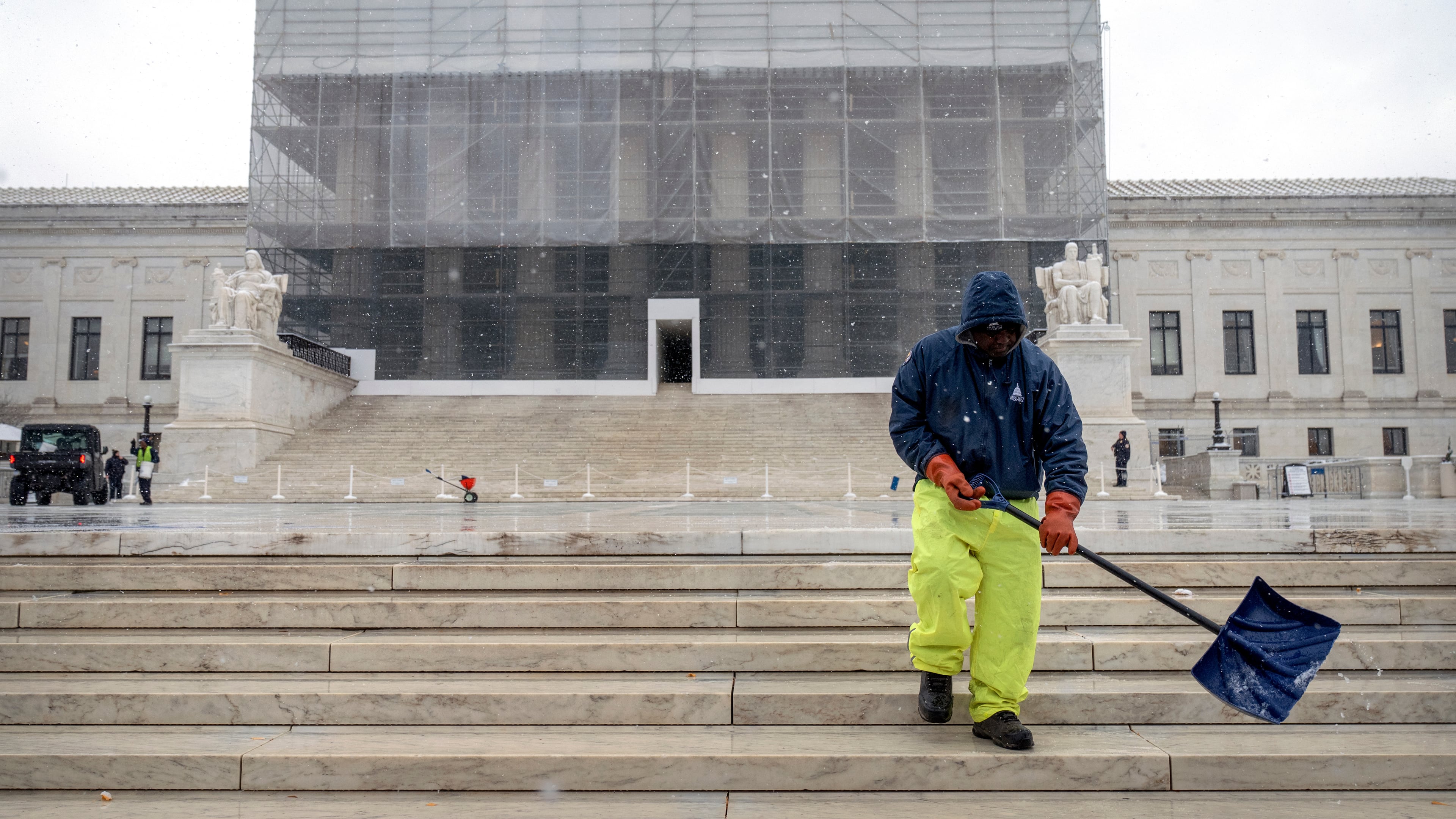 A worker shovels snow and ice in front of the Supreme Court building during the first snowfall of the winter season on Friday, Dec. 5, 2025, in Washington. (AP Photo/Mark Schiefelbein)