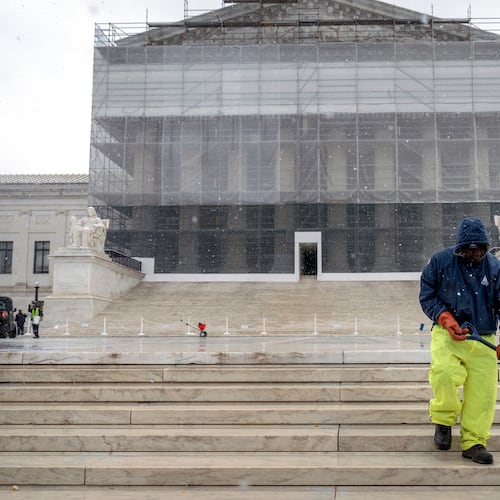 A worker shovels snow and ice in front of the Supreme Court building during the first snowfall of the winter season on Friday, Dec. 5, 2025, in Washington. (AP Photo/Mark Schiefelbein)