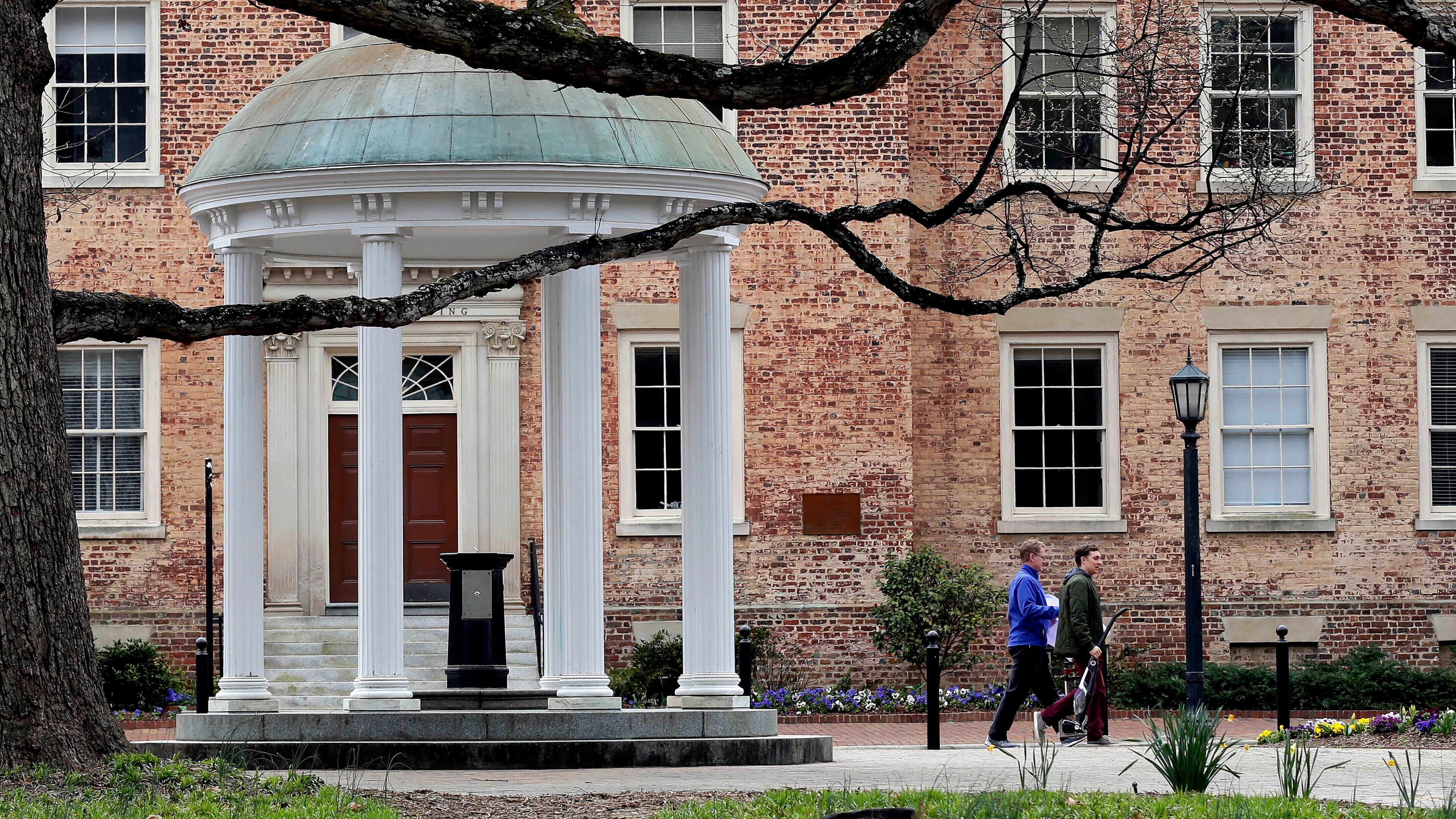 FILE - People walk through University of North Carolina campus March 18, 2020, in Chapel Hill, N.C. (AP Photo/Gerry Broome, File)