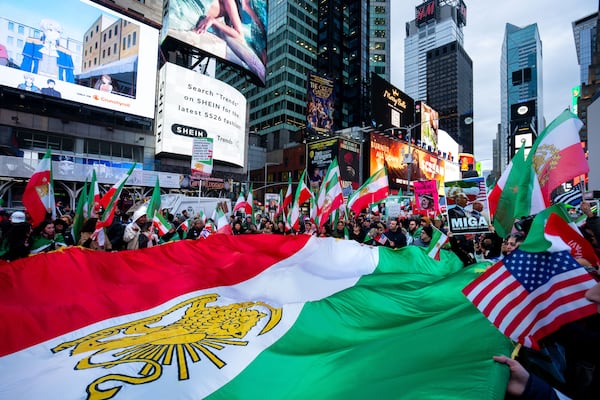People wave a large Iranian flag in Times Square on Sunday, March 15, 2026, at an anti-Iranian regime demonstration in support of Donald Trump and Israel's actions against the Iranian government. (Angelina Katsanis/AP)