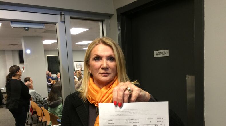 Perri Higbie shows a $795,458 water bill that her Brookhaven homeowners' association received from DeKalb County in August. Higbie and about 100 residents attended a water billing community meeting on Nov. 2, 2015. MARK NIESSE / MARK.NIESSE@AJC.COM