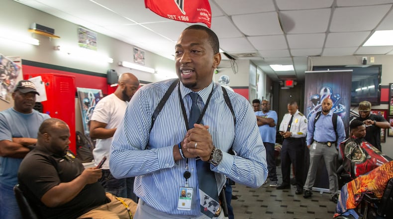 Tyrone Dennis leads a discussion with community members at Pro Cuts ATL, a barber shop off Martin Luther King in Atlanta. The Investigator with the Atlanta Police Department is trying to build better relations between cops and the community with informal gatherings called "Clippers & Cops," when there is no cause for confrontation. (Photo by Phil Skinner)