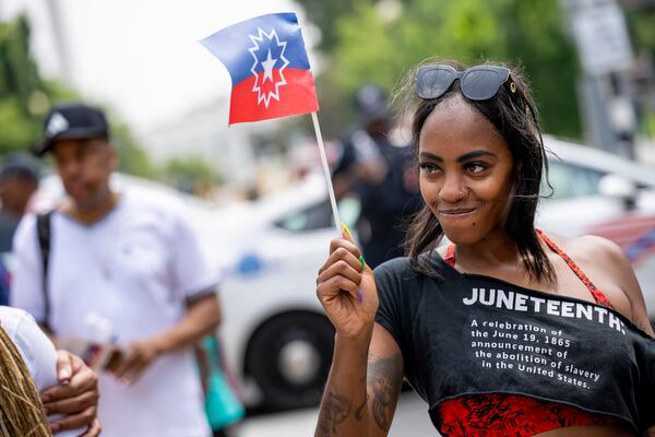 FILE - Chelsea Andrews, of Washington, waves the Juneteenth flag during a Juneteenth celebration at Black Lives Matter Plaza in Washington, Monday, June 19, 2023. (AP Photo/Andrew Harnik, file)