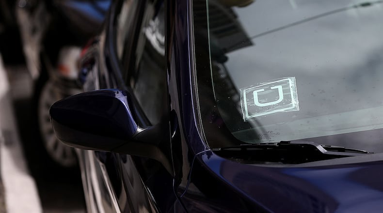 A sticker with the Uber logo is displayed in the window of a car. (Photo by Justin Sullivan/Getty Images)