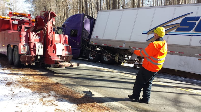 A tow truck pulls an 18-wheeler out of a ditch in south Fulton County on Thursday.