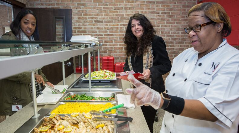 (left to right, all cq) Kelsey Darren & food service director Carol Cottrell listen to Kimberly Spear describe the lunch choices at Woodward Academy in Atlanta on January 30th, 2017. Woodward is the large employer AJC Top Workplace winner. (Photo by Phil Skinner)