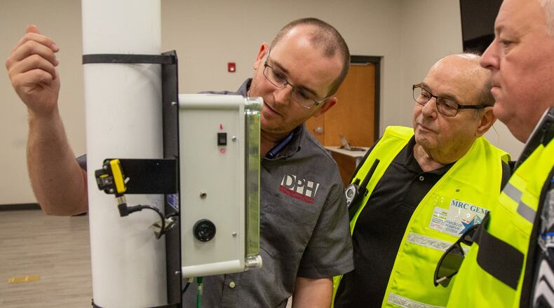 Daryl Farmer (from left), of GADPH, Arnie Zwickel and Mike Mester check a Portral Montior that scans for radioactivity before volunteers of the Medical Reserve Corps-Georgia East Metro (known as MRC GEM), participate in mock disaster training at the Gwinnett County Health Department in Lawrenceville. Photo by Phil Skinner
