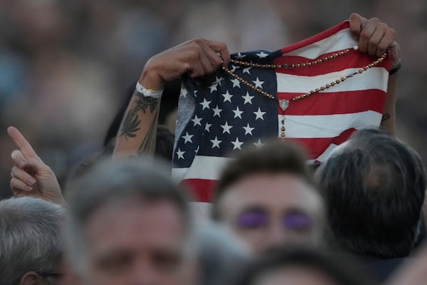 FILE - Faithful holds an American flag following the election of Pope Leo XIV at the Vatican, Thursday, May 8, 2025. (AP Photo/Andrew Medichini, File)