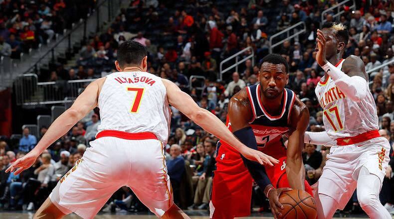 ATLANTA, GA - DECEMBER 27:  John Wall #2 of the Washington Wizards drives between Ersan Ilyasova #7 and Dennis Schroder #17 of the Atlanta Hawks at Philips Arena on December 27, 2017 in Atlanta, Georgia.  NOTE TO USER: User expressly acknowledges and agrees that, by downloading and or using this photograph, User is consenting to the terms and conditions of the Getty Images License Agreement.  (Photo by Kevin C. Cox/Getty Images)