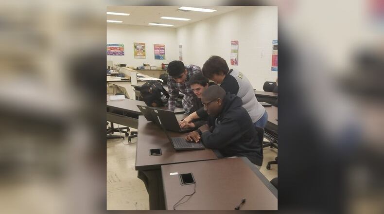Henry County students in the system's cybersecurity program huddling around their computers during class.