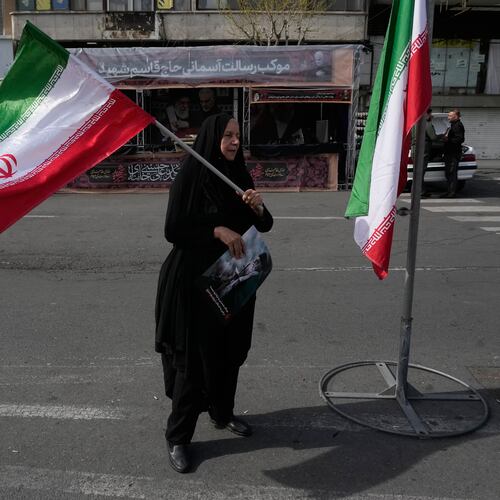 A woman waves an Iranian flag during a campaign in support of the government at the Enqelab-e-Eslami, or Islamic Revolution, square in downtown Tehran, Iran, Sunday, March 22, 2026. (AP Photo/Vahid Salemi)