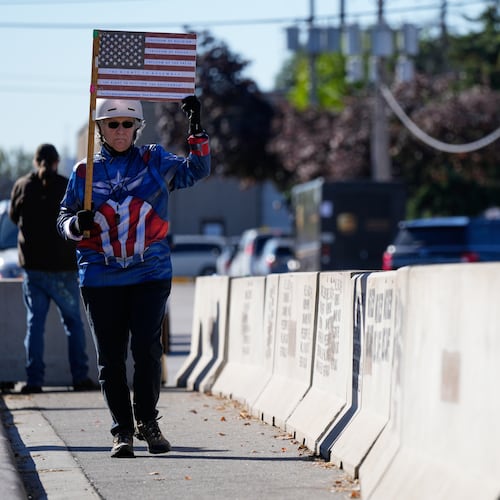 Jeanette Mancusi holds a American flag with the writing outside an ICE (U.S. Immigration and Customs Enforcement) processing facility in the Chicago suburb of Broadview, Ill., Monday, Oct. 20, 2025. (AP Photo/Nam Y. Huh)